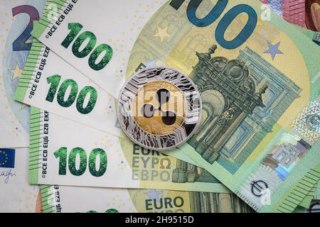 Ripple XRP physical coin laying on top of 100 Euro bills. Stock Photo