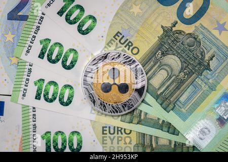 Ripple XRP physical coin laying on top of 100 Euro bills. Stock Photo