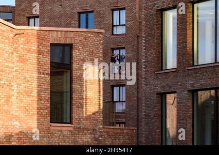 Window cleaner at work (abseiler, new housing, high-rise apartments building, safety) - Hudson Quarter, York city centre, North Yorkshire, England UK. Stock Photo