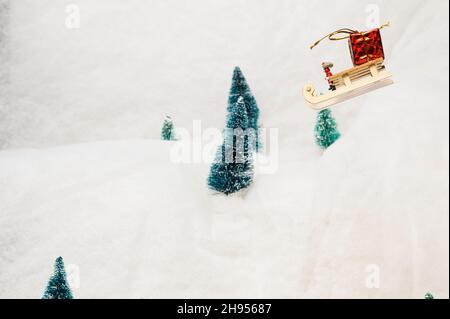 Miniature Santa Claus  flies through the snow mountain landscape with his sleigh Stock Photo