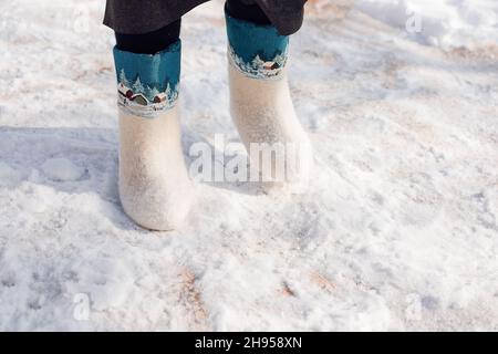 Close-up of felt boots. Man in white felt boots with pattern of organ on them stands on pure snow in winter, which fell after heavy snowstorm Stock Photo