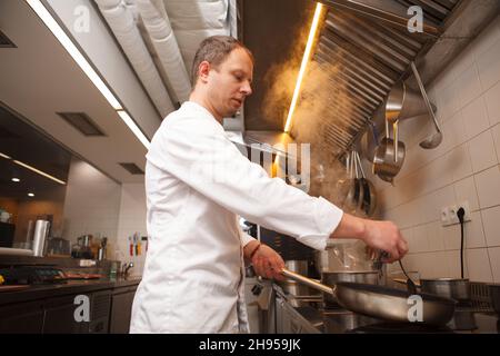 Low angle shot of a professional chef cooking using frying pan Stock Photo