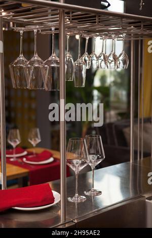 Vertical shot of clean wineglasses hanging from stemware rack at the restaurant Stock Photo