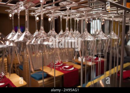 Close up of many clean wine glasses hanging from stemware rack Stock Photo