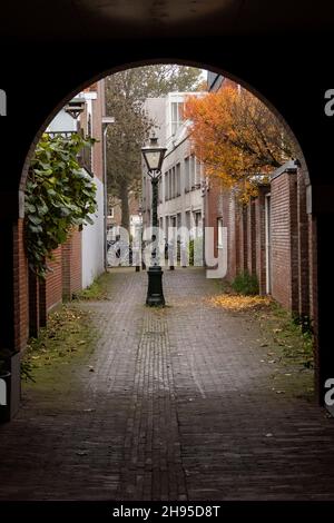 Looking through an arched alley walkway on Cananefatenpoort on a fall day in Leiden, Netherlands. Stock Photo