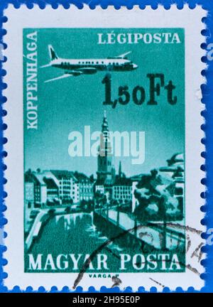 Photo of a green 1,50 ft Hungarian postage stamp featuring an illustration of a propellor driven passenger plane overflying Copenhagen Stock Photo