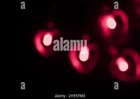 Four large red blurry red lights in the shape of a heart on a black background. Blurred abstract big red wallpaper for love theme, Valentine's day. Stock Photo