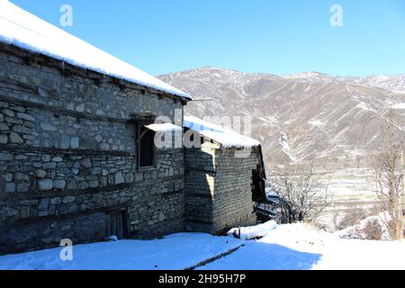 Winter landscape from Caucasian village Lahic - Azerbaijan. Fresh snow on old home in sunny day. Stock Photo