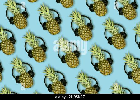 Lot of pineapples with headphones on a blue background - seamless pattern Stock Photo