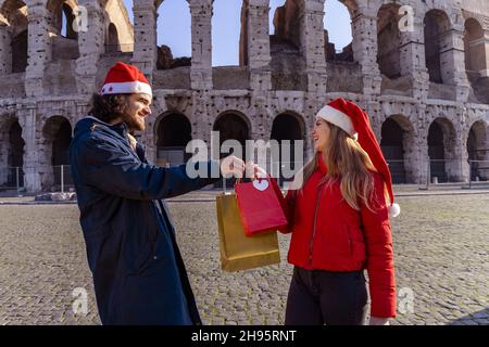 Christmas shopping time in Rome. Young man handing gifts to his girlfriend. Stock Photo
