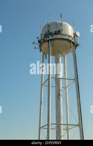 Water tower with dish and antennas for telecommunication on a blue sky Stock Photo