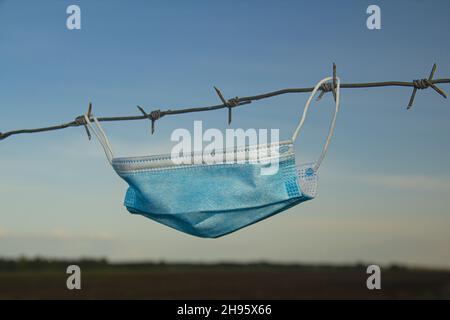 Conceptual image of a protective surgical mask on a barbed wire. Stock Photo