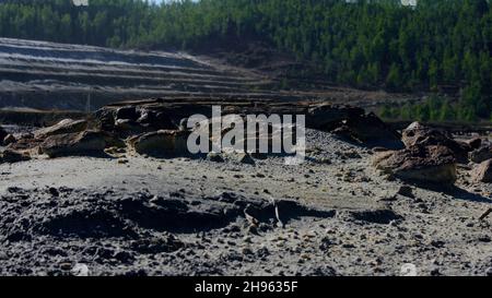 Rocks on background of quarry. Stock footage. Rocky relief of abandoned quarry with minerals on surface on forest background. Stock Photo