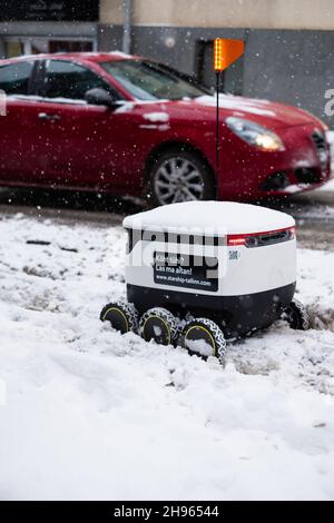 Tallinn, Estonia - December 4, 2021: Starship Technologies autonomous drone vehicle stuck in snow in winter. Self driving contactless delivery robot. Stock Photo