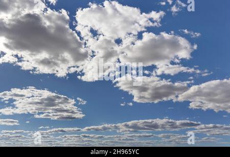 Bright sky background with few small clouds, strong sun shines through Stock Photo