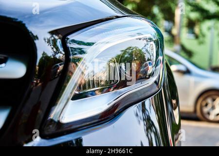 Headlight with halogen lamp on modern black car, close up Stock Photo