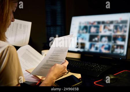 Woman reading paper documents at workplace at night. Overtime working and deadline concept Stock Photo