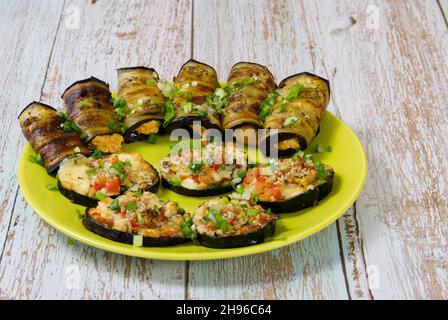 A festive snack of baked eggplant on a beautiful plate. Slices and rolls of vegetables with tasty filling. Stock Photo