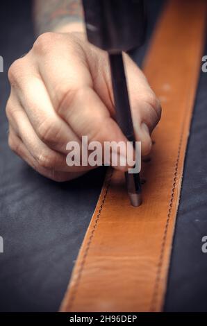 Leather Worker performing leatherwork on a new product piece in the work area Stock Photo