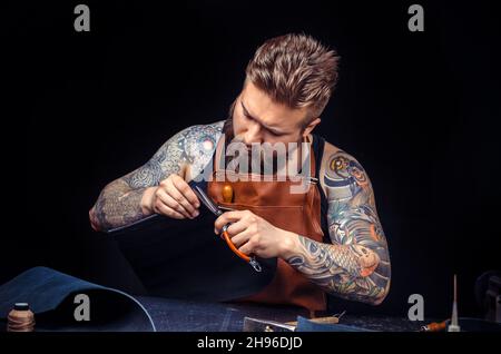 Leather Tanner cuts out leather goods Stock Photo