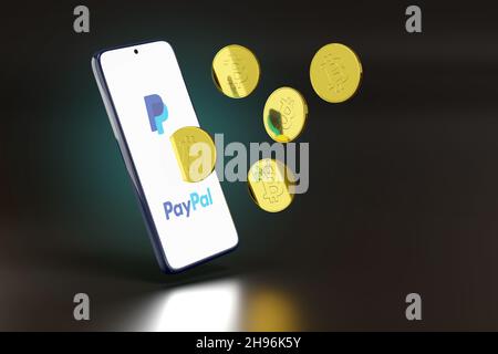 Buenos Aires, Argentina - December 4th, 2021: Mobile phone with Paypal logo and bitcoins coming out of the screen. 3d illustration. Stock Photo