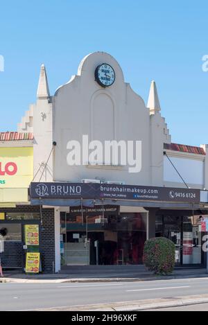 Part of a larger strip of shops, the Mark Mayne (Dry Cleaners) clock is mounted on an ornate parapet near the railway station at Lindfield, Sydney Stock Photo
