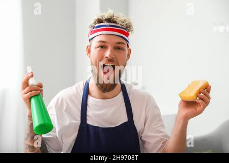Surprised young man with cleaning sponge and detergent at home Stock Photo