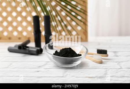 Bowl with activated charcoal tooth powder on table background Stock Photo