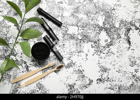 Jar with activated charcoal tooth powder, bamboo sticks and brushes on grunge background Stock Photo