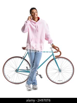 African-American teenage boy with bicycle talking by mobile phone on white background Stock Photo