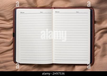 blank opened book on a brown fabric, template or background for graphic designing, closeup with copy space, flat lay Stock Photo