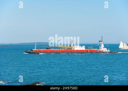 Mount St. Elias Tugboat pushing a barge at Casco Bay with Ram Island Lighthouse at the background, Portland, Maine ME, USA. Stock Photo