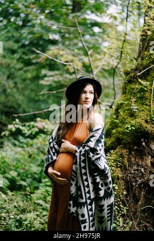 Pregnant woman hugs belly near olive tree Stock Photo - Alamy
