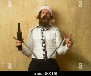 Funny crazy santa. Drunk bad santa holding bottle of whiskey or wine. Stock Photo