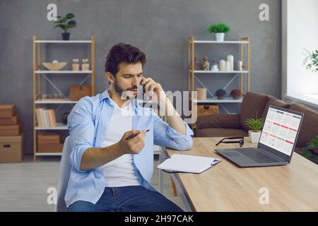 Man sitting at working desk, talking on cellphone and scheduling business meeting Stock Photo
