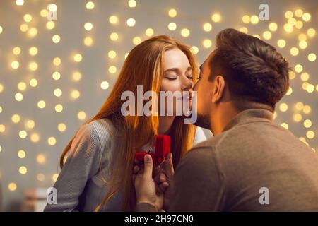 Happy young woman in love kissing her boyfriend after accepting his marriage proposal Stock Photo