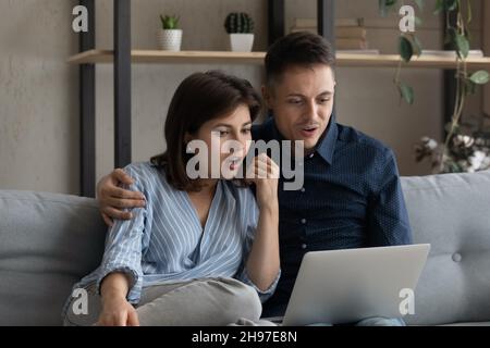 Excited surprised dating couple reading email message on laptop Stock Photo