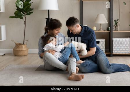 Happy laughing parents cuddling and tickling sweet little daughter Stock Photo