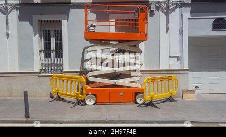 Electric mobile aerial work platform. Professional painters scissor lift parked over sidewalk