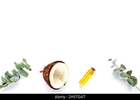 Fresh coconut and oil in a bottle, eucalyptus leaves on white background. Personal hygiene and natural cosmetics concept. Top view, flat lay, copy Stock Photo