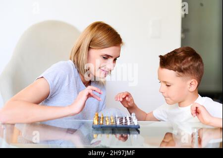 Caucasian Mother And little Son Playing Chess At Home Stock Photo