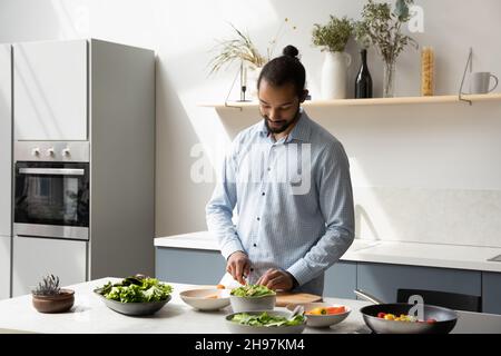 Happy young African American man cooking in modern kitchen. Stock Photo
