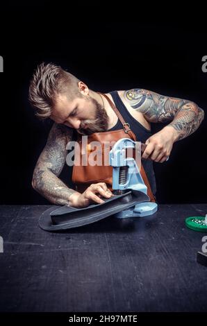 Leather Craftsman performs leather working for a new product in the work area Stock Photo