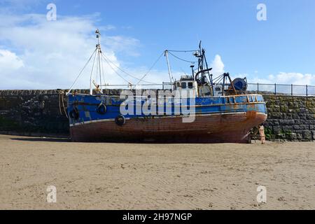A boat left high and dry on the sand by the receding tide at Barry, south Wales, UK Stock Photo
