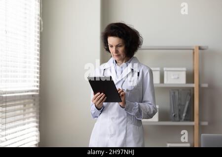 Serious mature female doctor using tablet computer Stock Photo