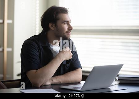 Thoughtful dreamy man thinking over work project ideas at workplace Stock Photo