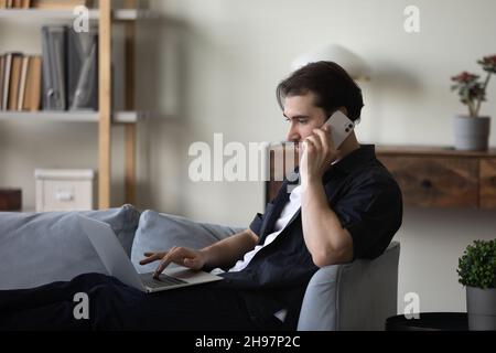 Serious busy freelance worker resting on couch, using laptop computer Stock Photo