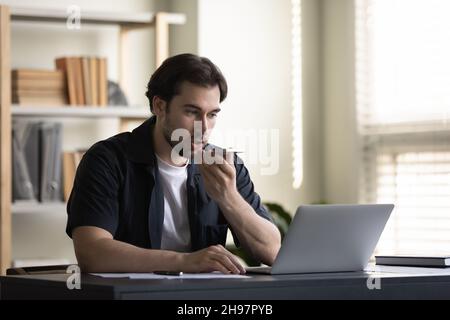 Serious millennial business man recording audio message on smartphone Stock Photo