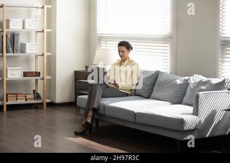 Middle aged business lady using laptop computer on couch Stock Photo
