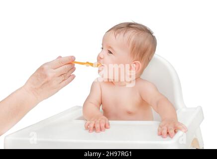 The first feeding of the baby. Hand holds out a spoon with mashed potatoes to a child Stock Photo